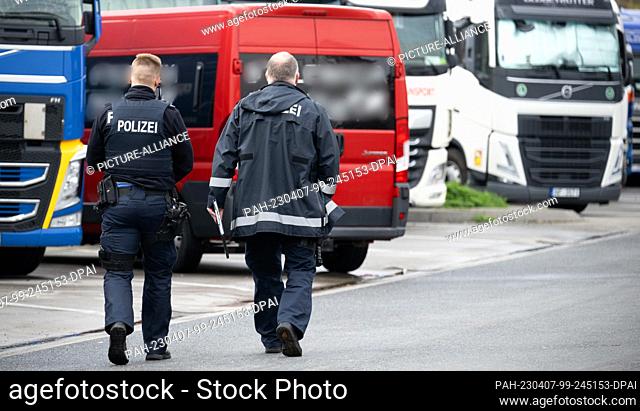 07 April 2023, Hesse, Weiterstadt: Police officers walk towards a red minibus that had come to the rest area accompanied by a private Polish security service...