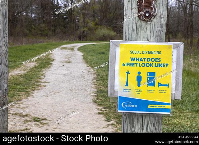 Washington Township, Michigan - A sign at a trailhead in Stony Creek Metropark reminds hikers to remain the correct social distance apart during the coronavirus...