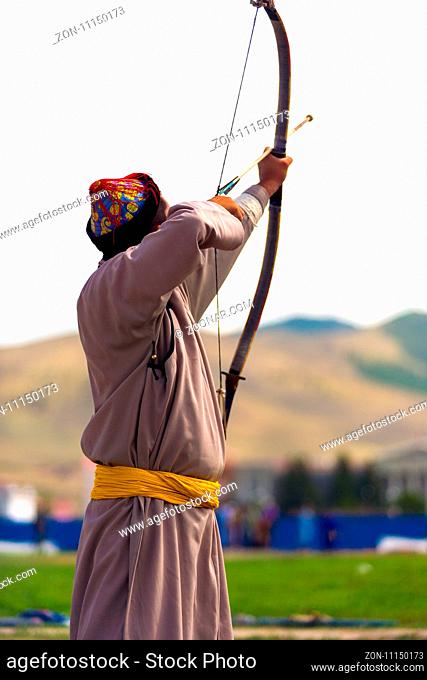 Ulaanbaatar, Mongolia - June 11, 2007: Rear view of male archer pulling bowstring, aiming at target at Naadam Festival archery event