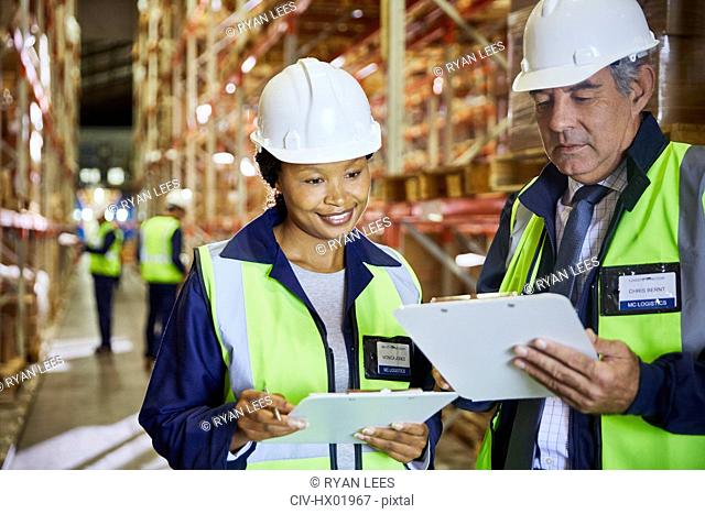 Manager and worker with clipboards meeting in distribution warehouse