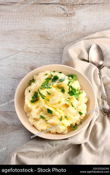 A plate of mashed potatoes poured with melted butter and seasoned with greens