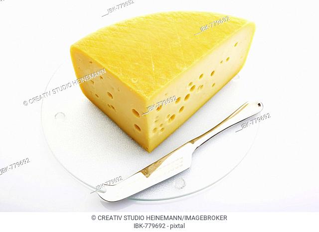 Cheese wedge on glass cutting board with silver cheese knife