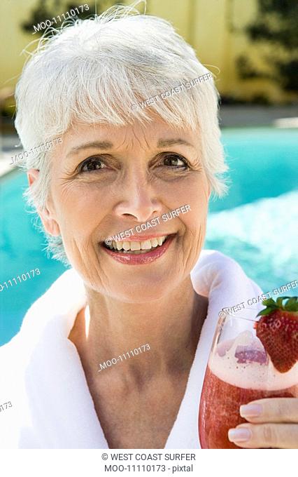 Portrait of senior woman holding strawberry cocktail