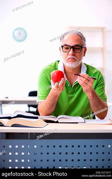 Senior male student eating apple during exam preparation