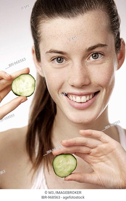 Teenage girl, woman, 17 years-old, holding cucumber slices, smiling