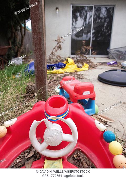 Red childs toy in messy yard inside of a foreclosed home in Fresno, California, United States