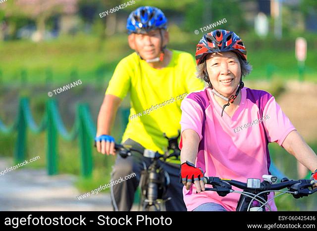 Happy senior couple exercising with bicycles in the park