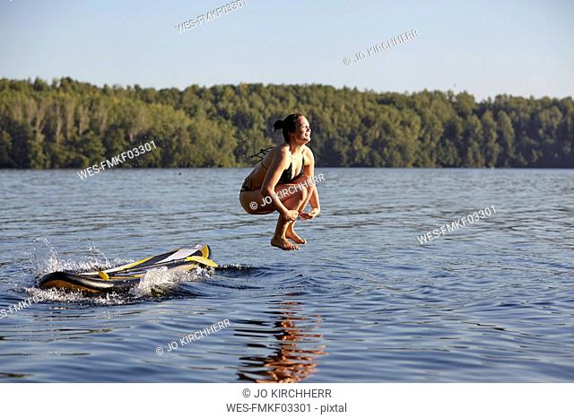 Woman jumping into water from paddleboard