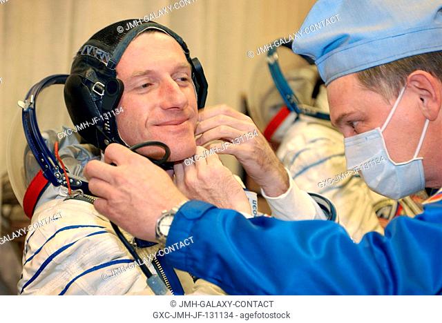 Astronaut C. Michael Foale, Expedition 8 mission commander and NASA ISS science officer, dons his spacesuit with the assistance of technicians October 18, 2003