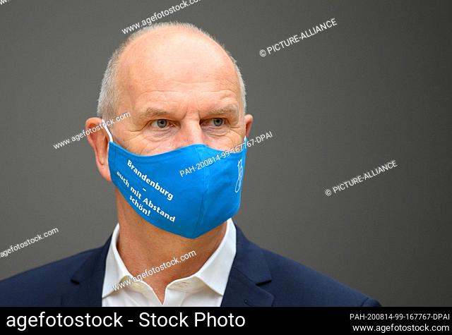 14 August 2020, Brandenburg, Potsdam: Dietmar Woidke (SPD), Minister President of Brandenburg, wears a blue mouth-nose guard with the inscription ""Brandenburg...