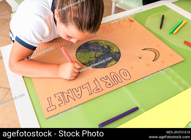 Girl drawing on cardboard paper at table in living room