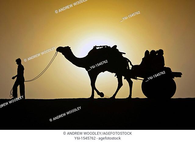 Silhouette of man and camel cart sunrise Thar Desert near Khuri Rajasthan India