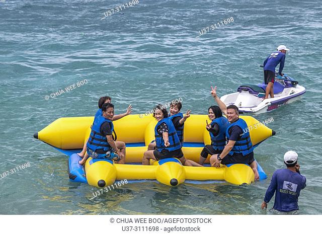 Happy people having fun on banana boat in Bai Tranh beach, Vietnam