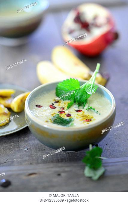 Curry and banana soup with coconut milk and pomegranate seeds