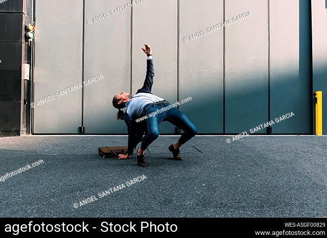 Businessman bending over backwards on footpath