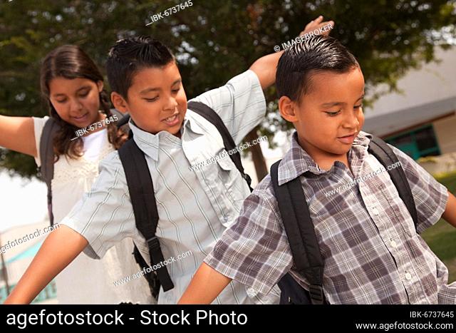 Cute brothers and sister with backpacks having fun walking to school