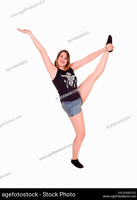 A pretty woman dancing in the studio is jeans shorts with her hands raised and singing, isolated for white background