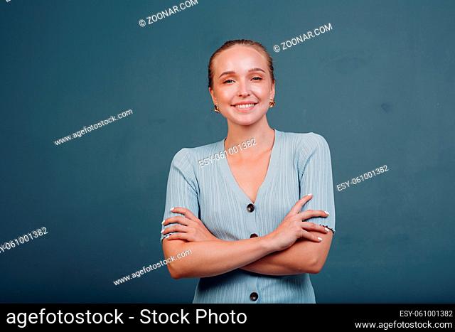 Portrait of young smiling european woman. Beautiful happy blonde girl wears t-shirt and looks at camera. Studio shoot isolated on blue background