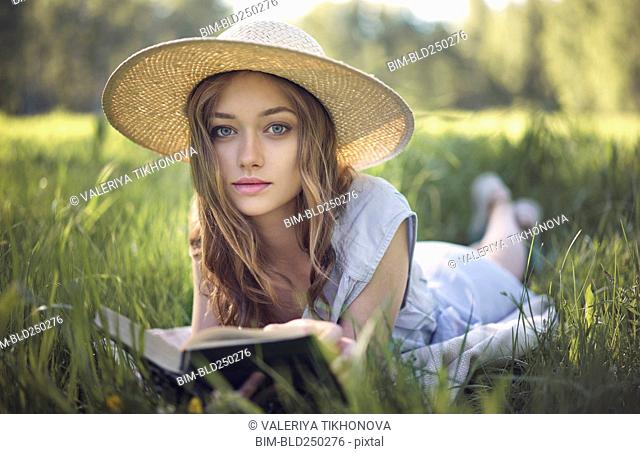 Caucasian woman laying in grass reading book