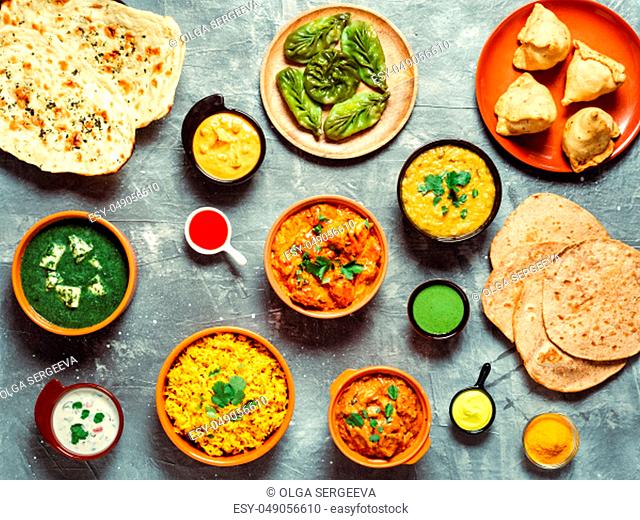 Indian cuisine dishes: tikka masala, dal, paneer, samosa, chapati, chutney, spices. Indian food on gray background. Assortment indian meal top view or flat lay