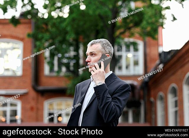 Businessman talking on smart phone in front of buildings
