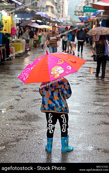 Kowloon, Hong Kong - April 23, 2017: Child With Red Umbrella at Street Market Rainy Day in Kowloon, Hong Kong