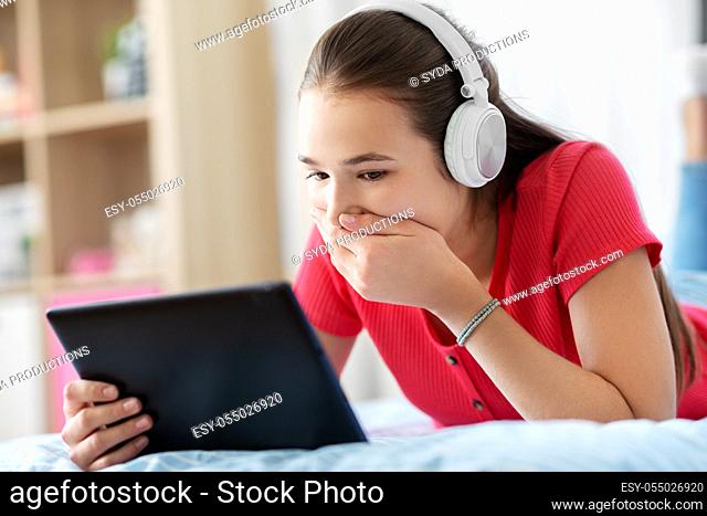 girl in headphones listening to music on tablet pc