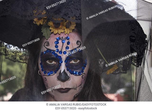 Mexican woman wearing makeup, veil hat an yellow flowers over to celebrating the Day of the Dead