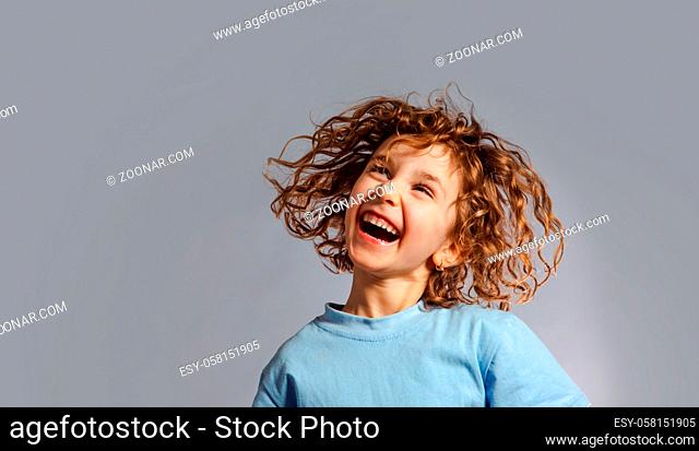 Little girl jumps on a gray background, face close up