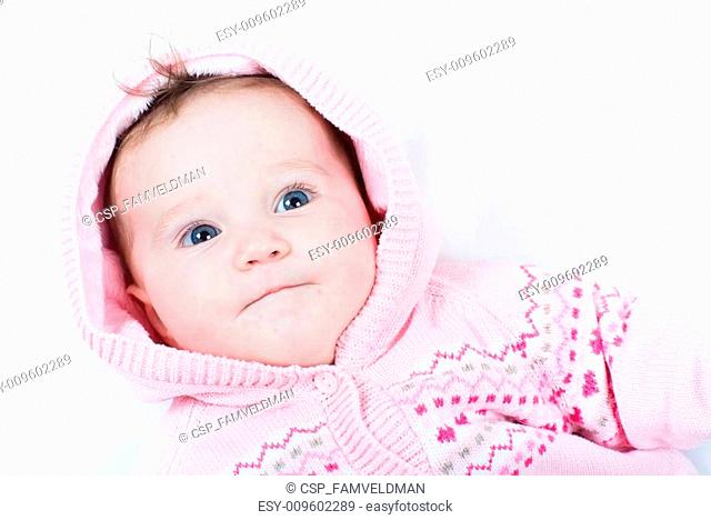 Adorable baby girl in a pink knitted jacket with red hearts