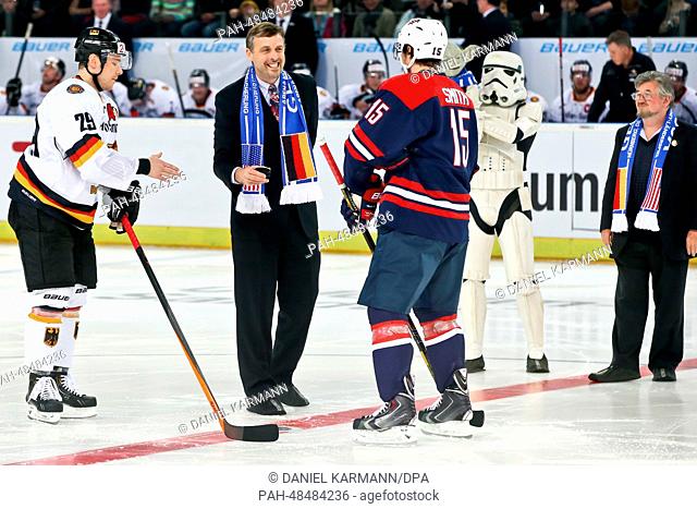 American consul general in Munich Bill Moeller (2-L) holds the puck next to Germany's Alexander Barta (L) and USA's Craig Smith during the world ice hockey...