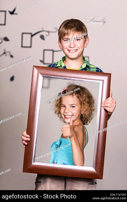 Happy brother holding portrait with his sister each is located inside her own frame