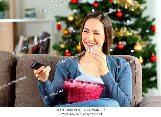 Woman watching tv in christmas sitting on a couch in the living room at home