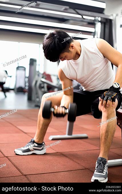 young handsome asian man works out in modern gynm