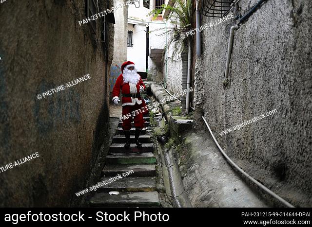 15 December 2023, Venezuela, Caracas: A man dressed as Santa Claus walks through an alley in the poor neighborhood of Petare during the handover of the ""A toy