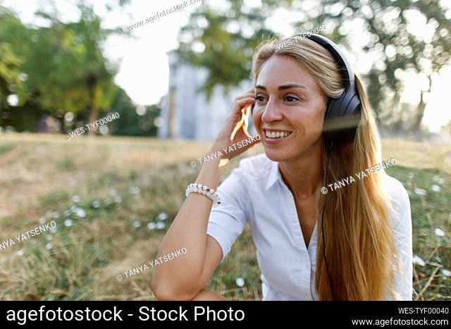 Blond woman listening music on wireless headphones