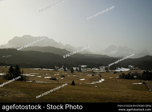 24 February 2021, Bavaria, Mittenwald: The sky above the mountains in the Wetterstein range is clouded by the Sahara sand in the air