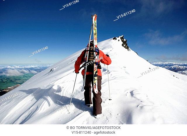 Off-piste skier climbing snow covered mountain with telemark skies