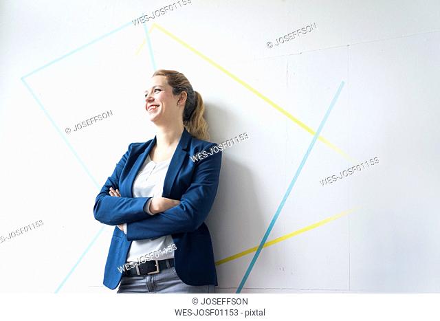 Businesswoman standing in office with arms crossed