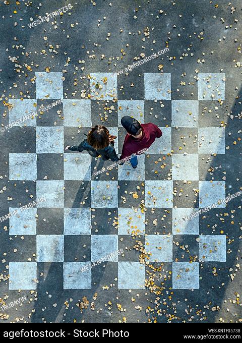 Couple walking on chessboard painted on asphalt