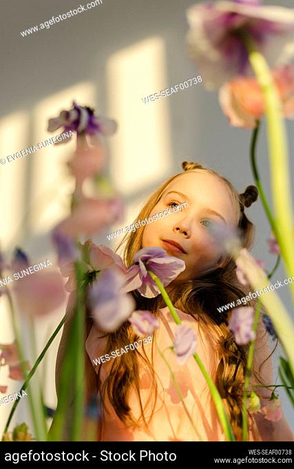 Thoughtful girl standing behind fresh flowers