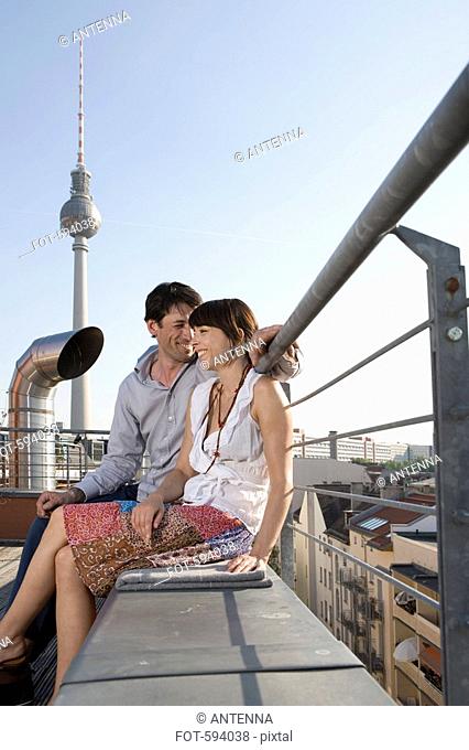 A man and a woman sitting together on a rooftop terrace