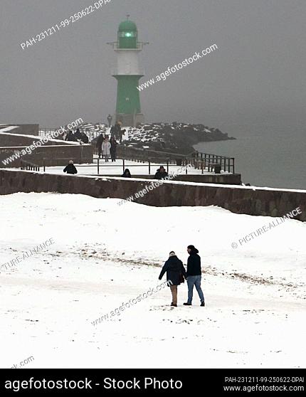 PRODUCTION - 07 December 2023, Mecklenburg-Western Pomerania, Warnemünde: Walkers are out and about on the snow-covered beach of the Baltic seaside resort
