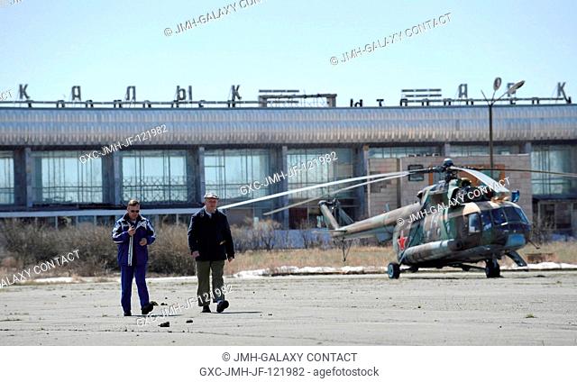 Steve Lindsey (left), chief of NASA's astronaut office, and interpreter Paul Kharmats wait at the Arkalyk airport in Kazakhstan as Russian helicopters are...