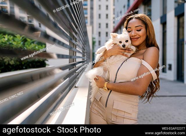 Young woman hugging dog on footpath