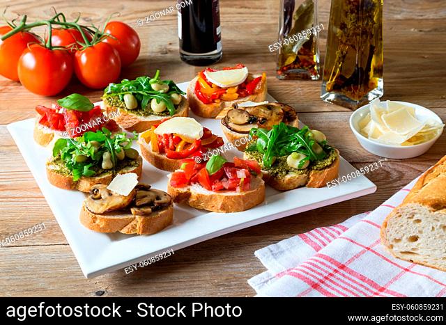 Bruschetta mit Bohnen und Rucola, Pilze, Ziegenkäse auf einem Holzbrett