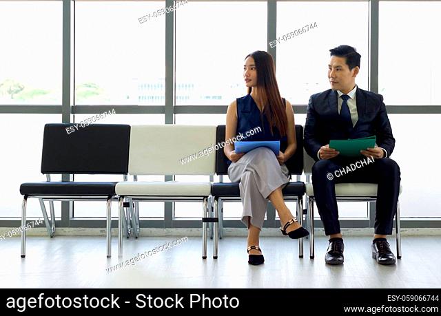 Asian business people waiting for job interview. Both of them looking at the same direction