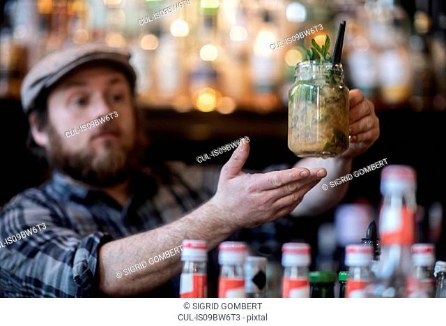 Barman serving jar glass cocktail in traditional Irish public house