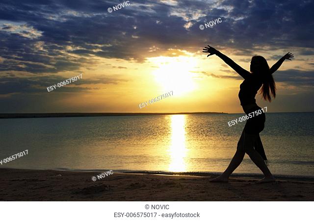 Elegant lady dancing sportive aerobics at the beach during sunset
