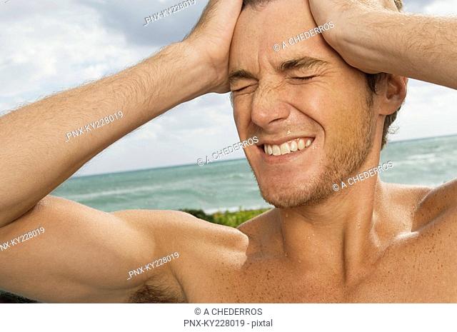 Man holding his head in pain on the beach